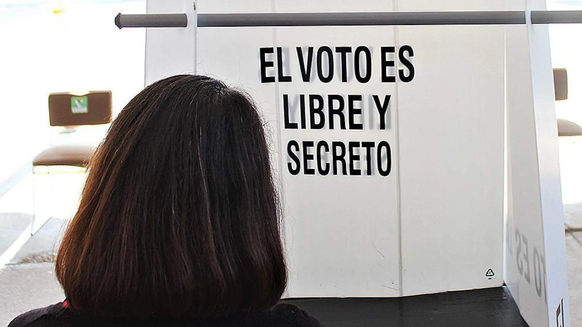 Mujer frente a una casilla de votación